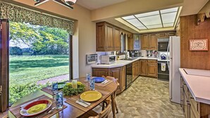 A modern kitchen with wooden cabinets, a central island, and a large window overlooking a garden. - 3 Mi to Silver Lake: Traverse City Home w/ Deck (Traverse City)