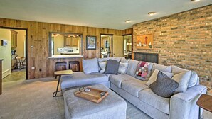 A modern living room with a sectional sofa, a wooden coffee table, and a brick accent wall. - 3 Mi to Silver Lake: Traverse City Home w/ Deck (Traverse City)