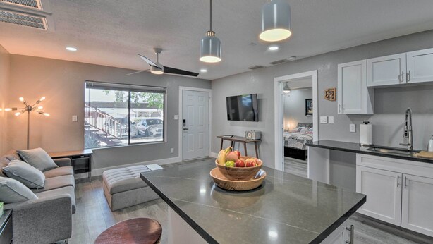 A modern kitchen with white cabinets, a large island with a fruit bowl, and a dining area with a sofa and a coffee table. - Peaceful Apache Junction Condo ~ 1 Mi to Downtown! (Apache Junction)
