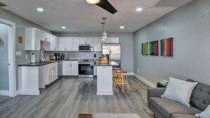 A modern kitchen with white cabinetry, a central island, and a dining area with bar stools. - Peaceful Apache Junction Condo ~ 1 Mi to Downtown! (Apache Junction)