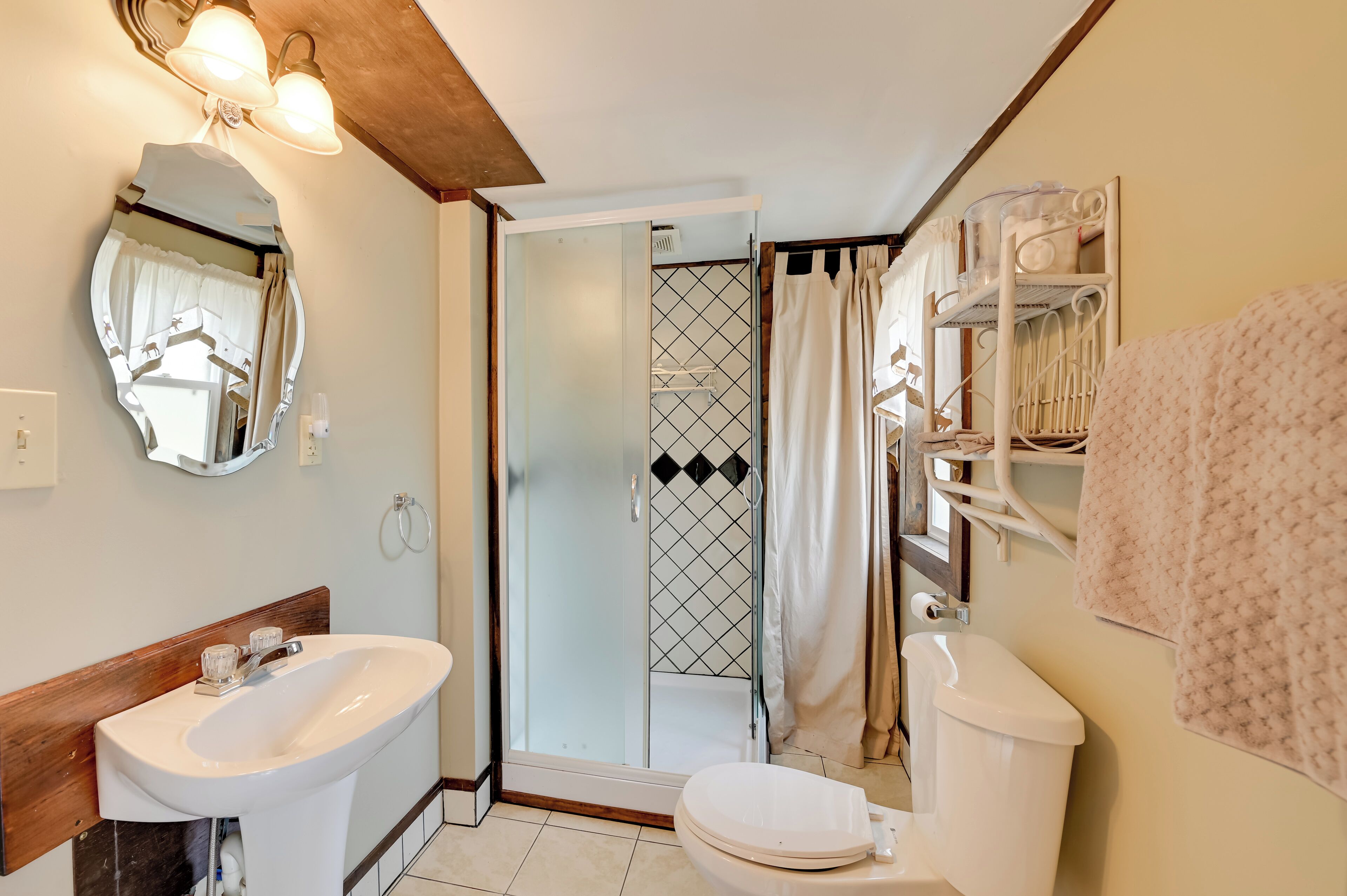 Un baño con lavamanos blanco, inodoro y cabina de ducha con paredes de vidrio.