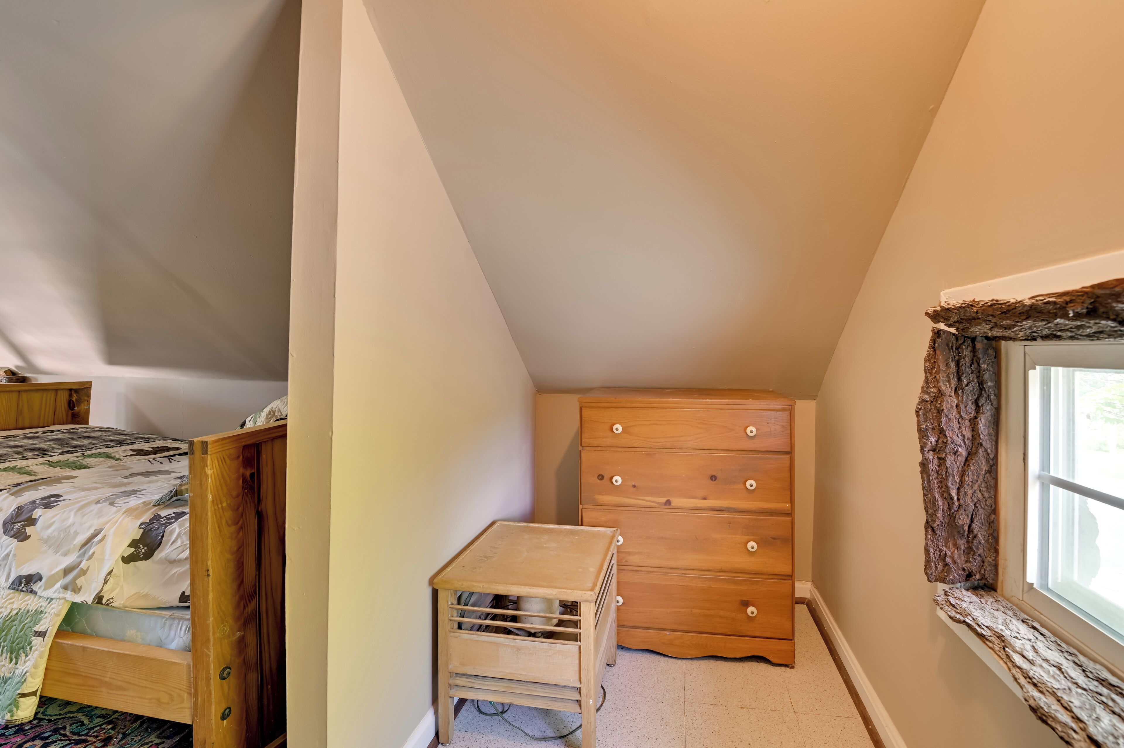 Une chambre à coucher avec un lit en bois, une commode et une petite table.