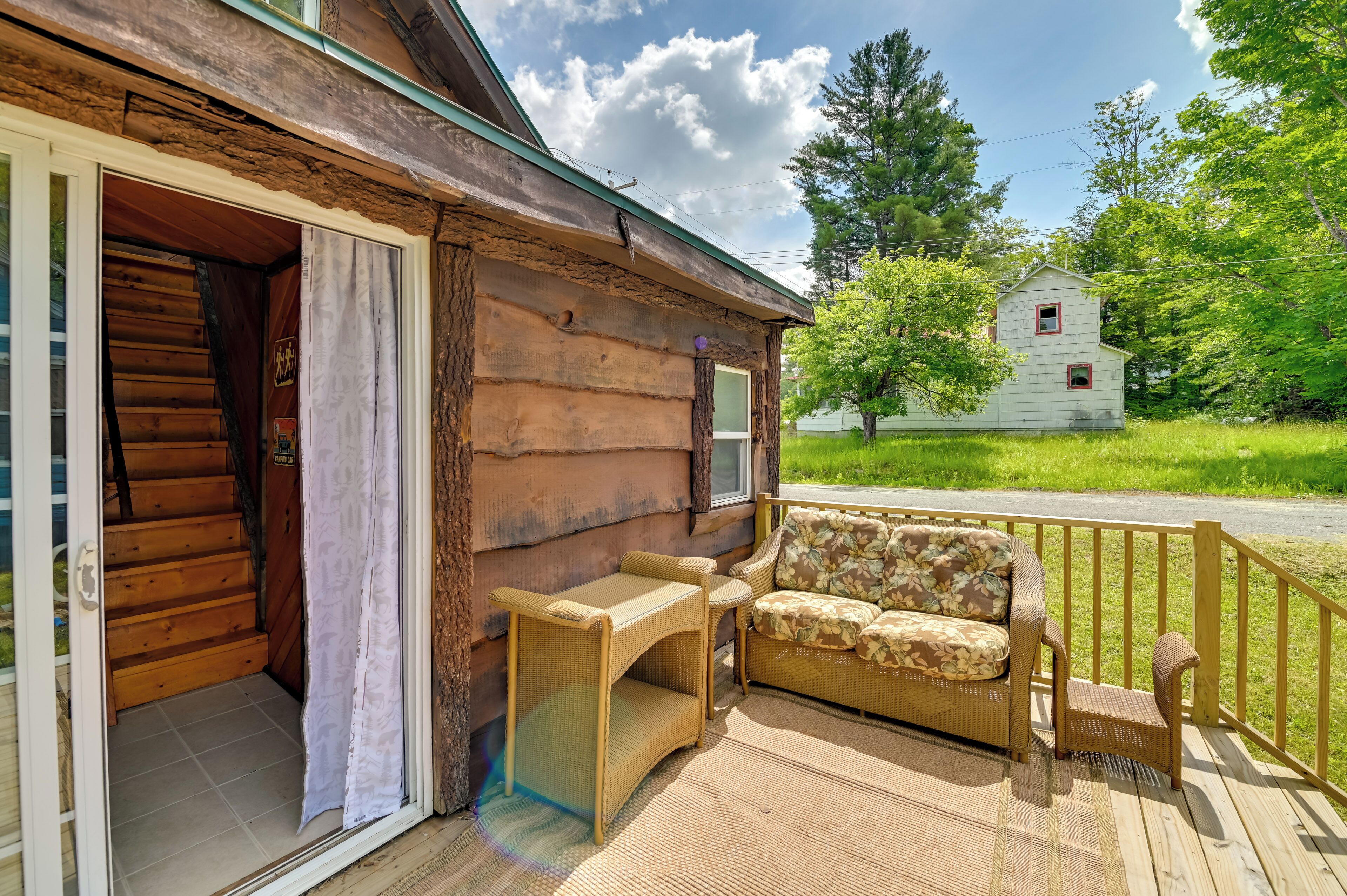 A wooden cabin with a porch, a wicker sofa, and a small table.