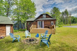 Un chalet rustique doté d’une véranda, d’un espace salon extérieur et d’un foyer.