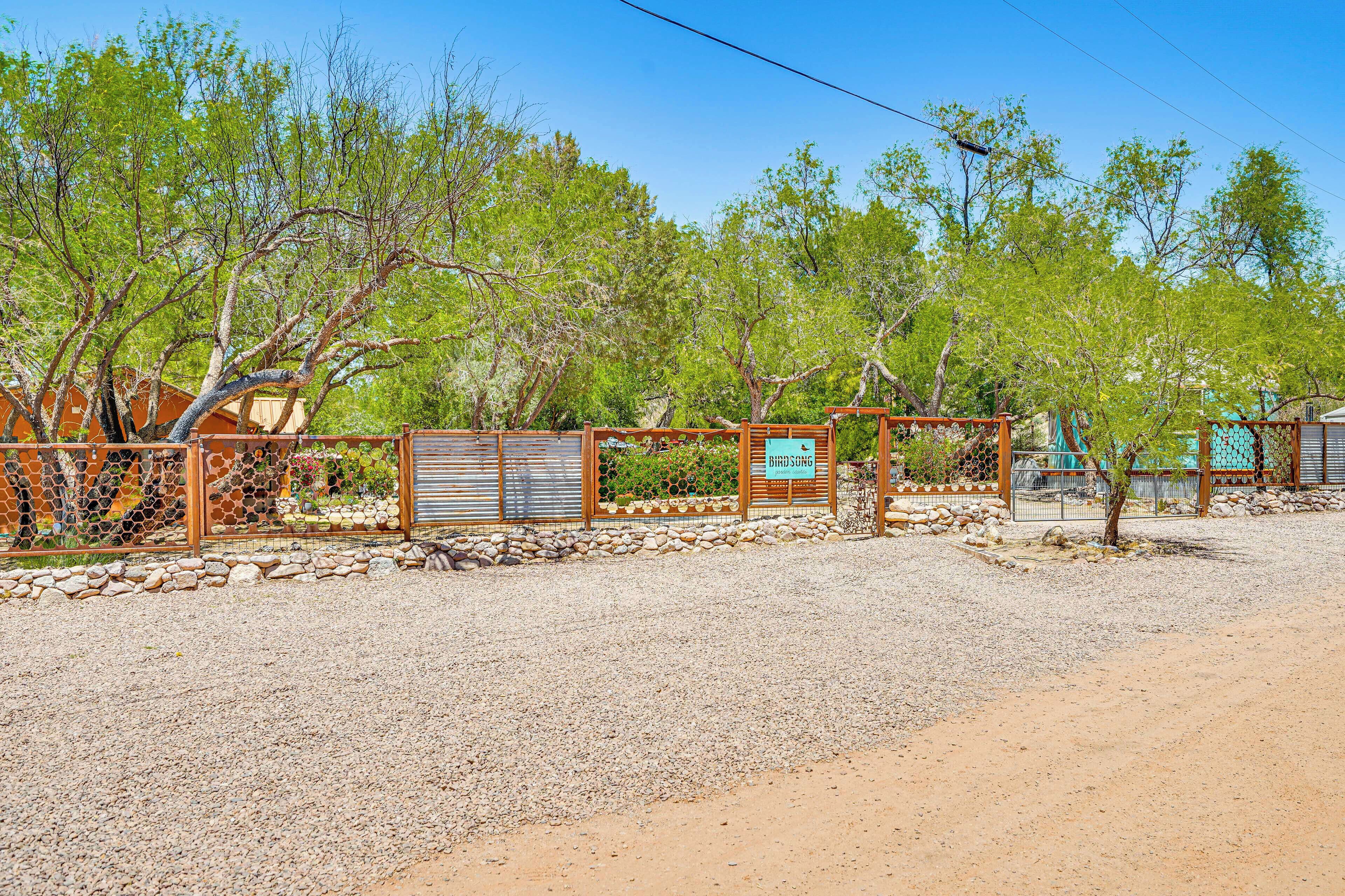 A fenced outdoor area with a gravel path, trees, and a building with a sign that reads "Birdsong."