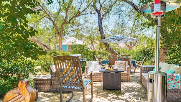 An outdoor patio with wicker furniture, a metal heater, and a decorative bird sculpture.