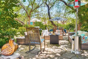An outdoor patio with wicker furniture, a metal heater, and a decorative bird sculpture. - Casa Paloma Studio: Artsy & Airy w/ Hot Tub Access (Patagonia)