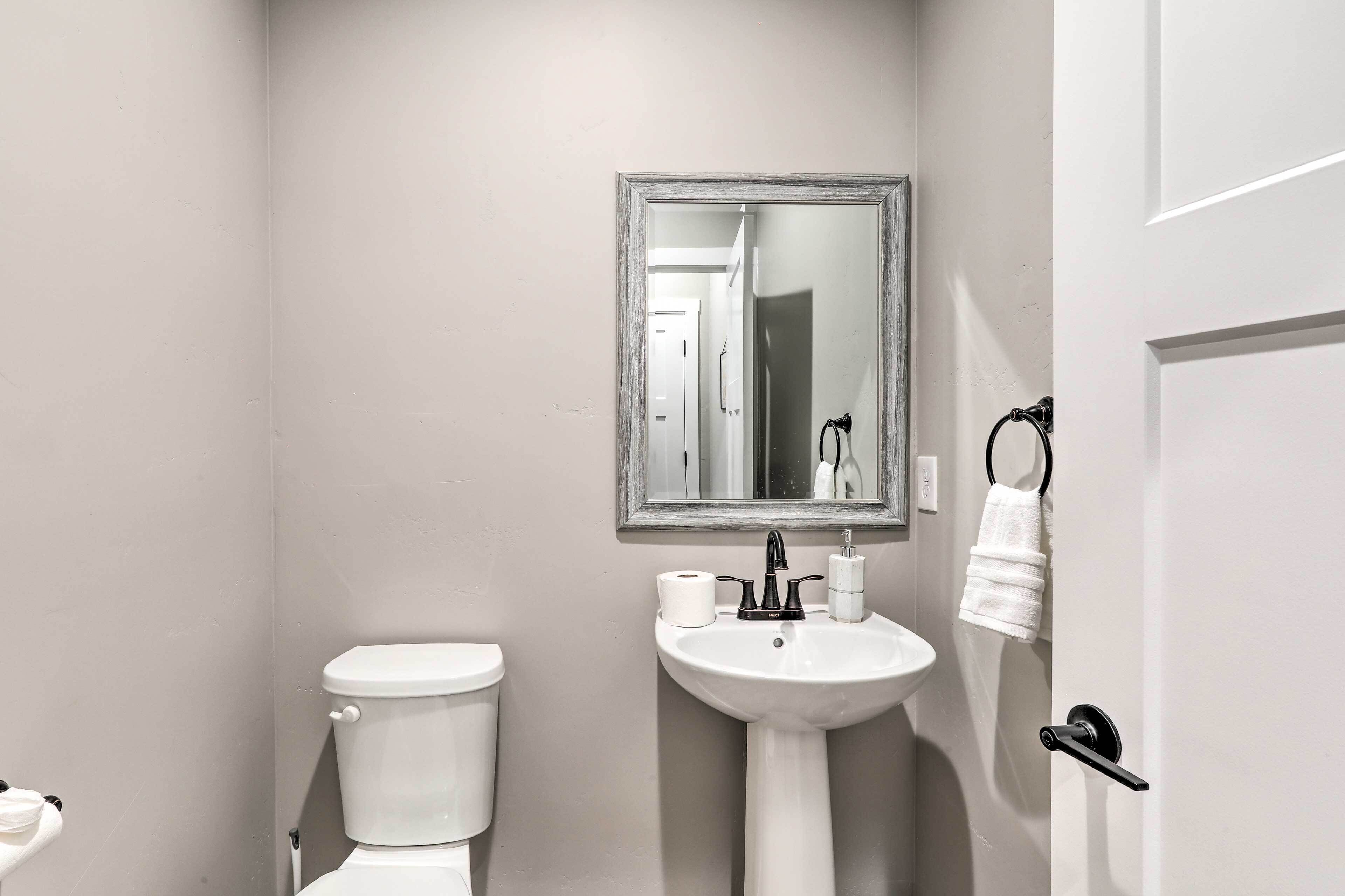 Een kleine badkamer met toilet, wastafel en spiegel.