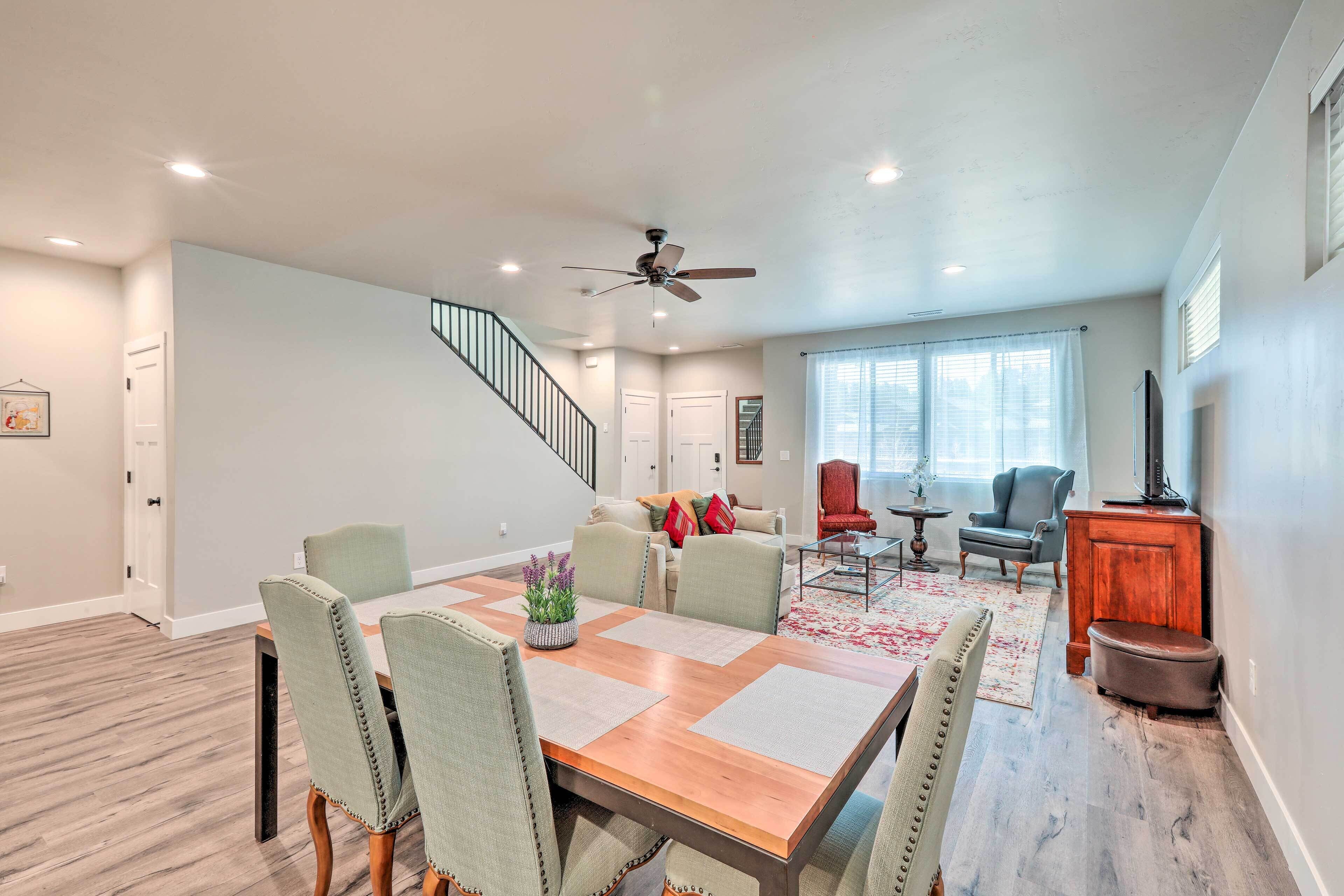 A spacious living room with a dining area, a staircase, and a television.
