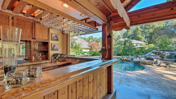 A wooden bar area with a pool view, clear glass containers, and a rustic setting. - Lavish Sonora Suite on 10 Acres w/ Shared Pool! (Sonora)