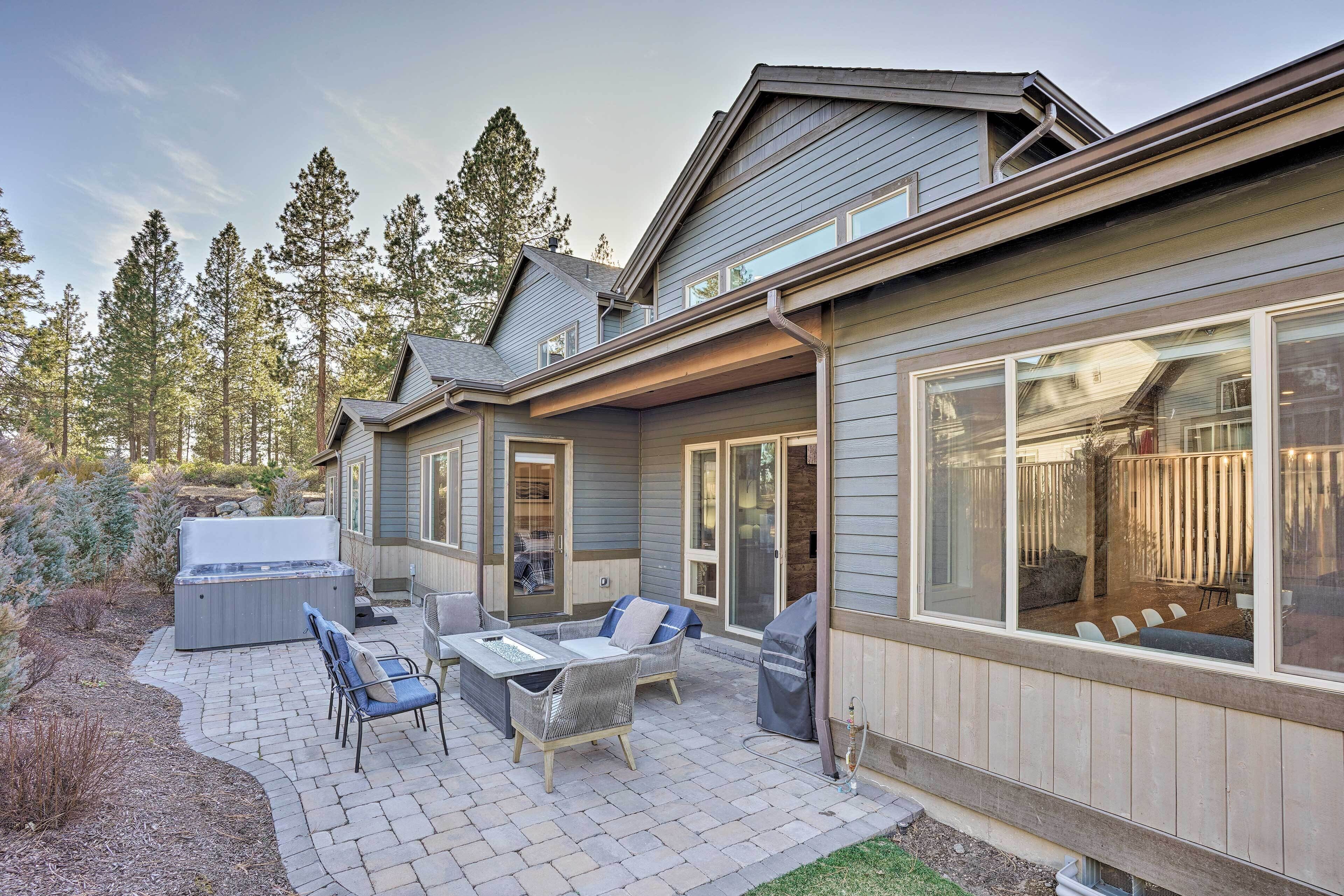 A house with a patio area featuring outdoor furniture, a hot tub, and a barbecue grill.