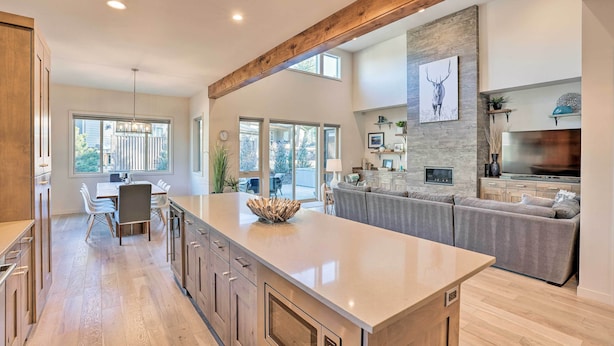 A spacious kitchen with a large island, wooden beams, and a stone accent wall. - Luxury Mt Bachelor Retreat w/ Hot Tub & Patio (Bend)