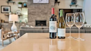 A table with two wine bottles and two wine glasses in a modern living room. - Luxury Mt Bachelor Retreat w/ Hot Tub & Patio (Bend)
