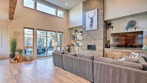 A spacious living room with a large sectional sofa, a fireplace, and a television. - Luxury Mt Bachelor Retreat w/ Hot Tub & Patio (Bend)