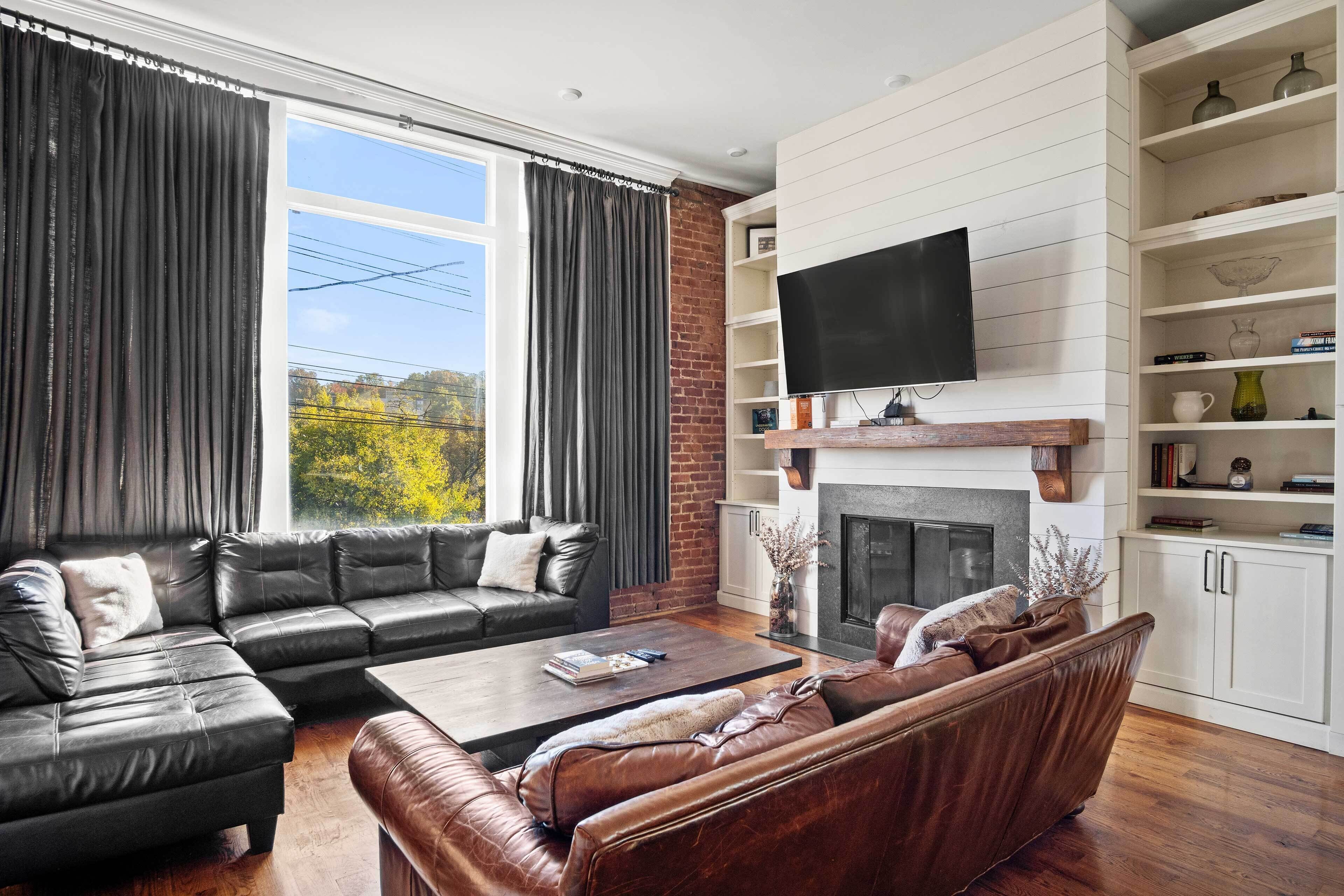 A modern living room with a sectional sofa, a coffee table, and a fireplace.