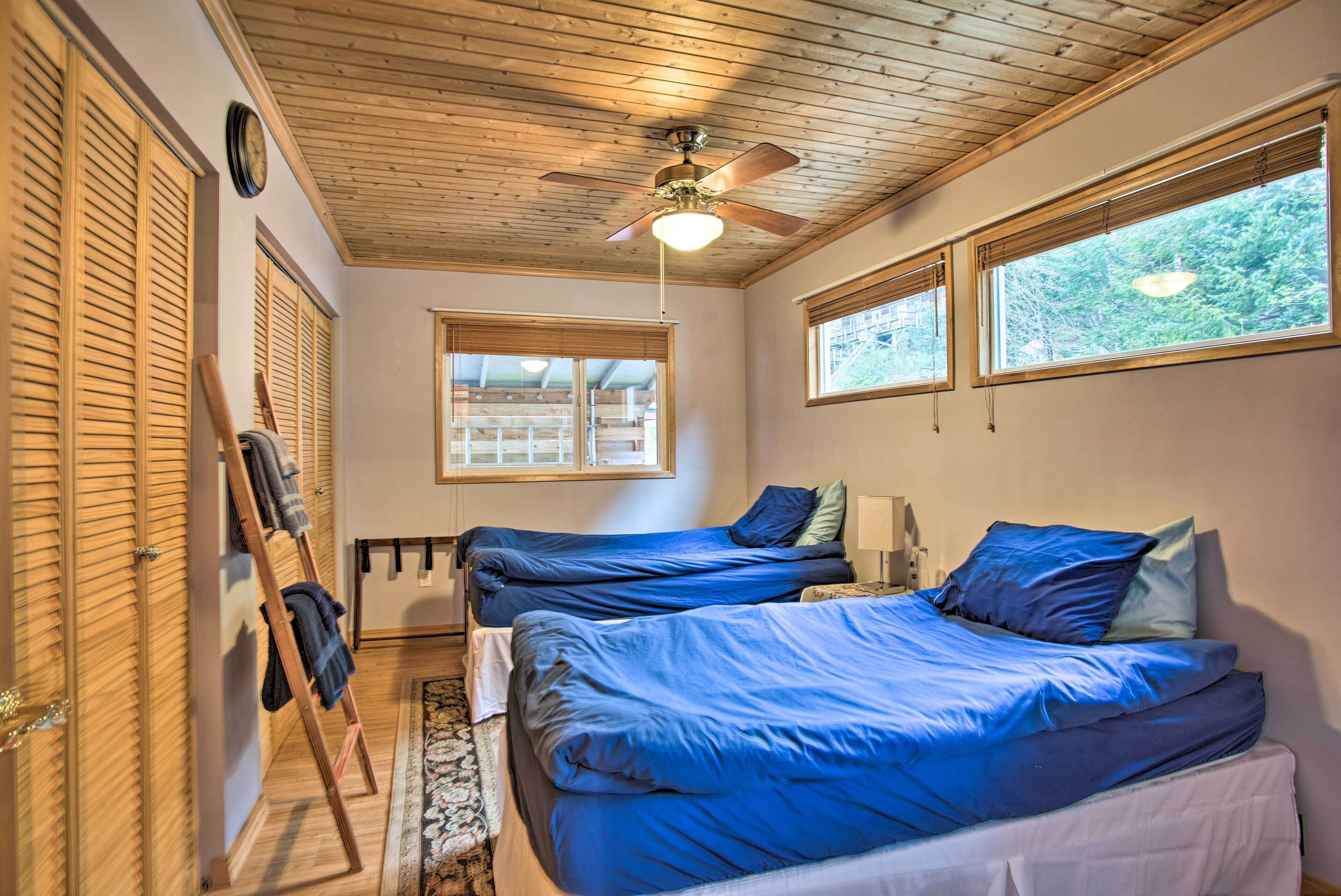 Ein Schlafzimmer mit zwei Betten, einem Deckenventilator, einer Uhr und Fenstern mit Jalousien.