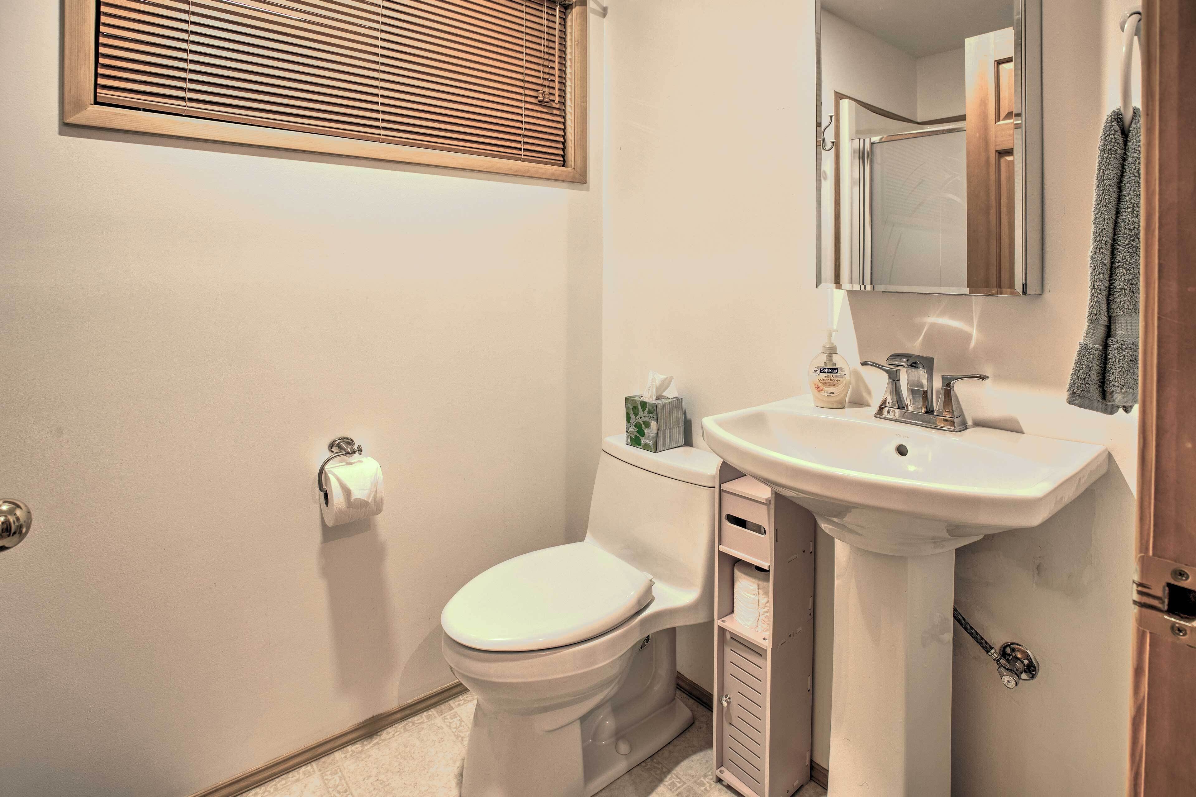 A bathroom with a toilet, sink, and a mirror above the sink.