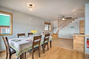 A dining area with a wooden table set for six, a ceiling fan, and a staircase leading to an upper level.
