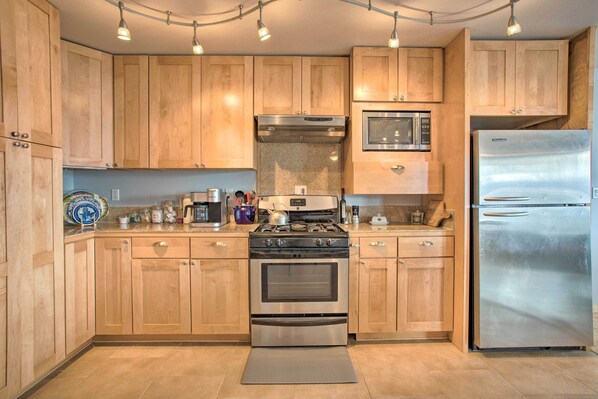 A kitchen with wooden cabinets, a stainless steel refrigerator, a stove, and a microwave.
