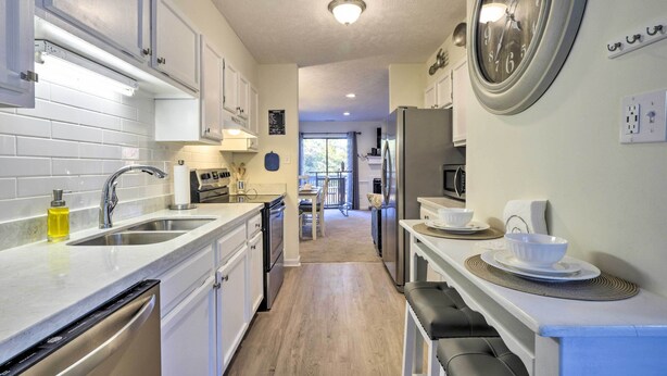 A modern kitchen with white cabinetry, stainless steel appliances, and a large wall clock. - Modern Townhome w/ Deck & Golf Course Views! (Pinehurst)