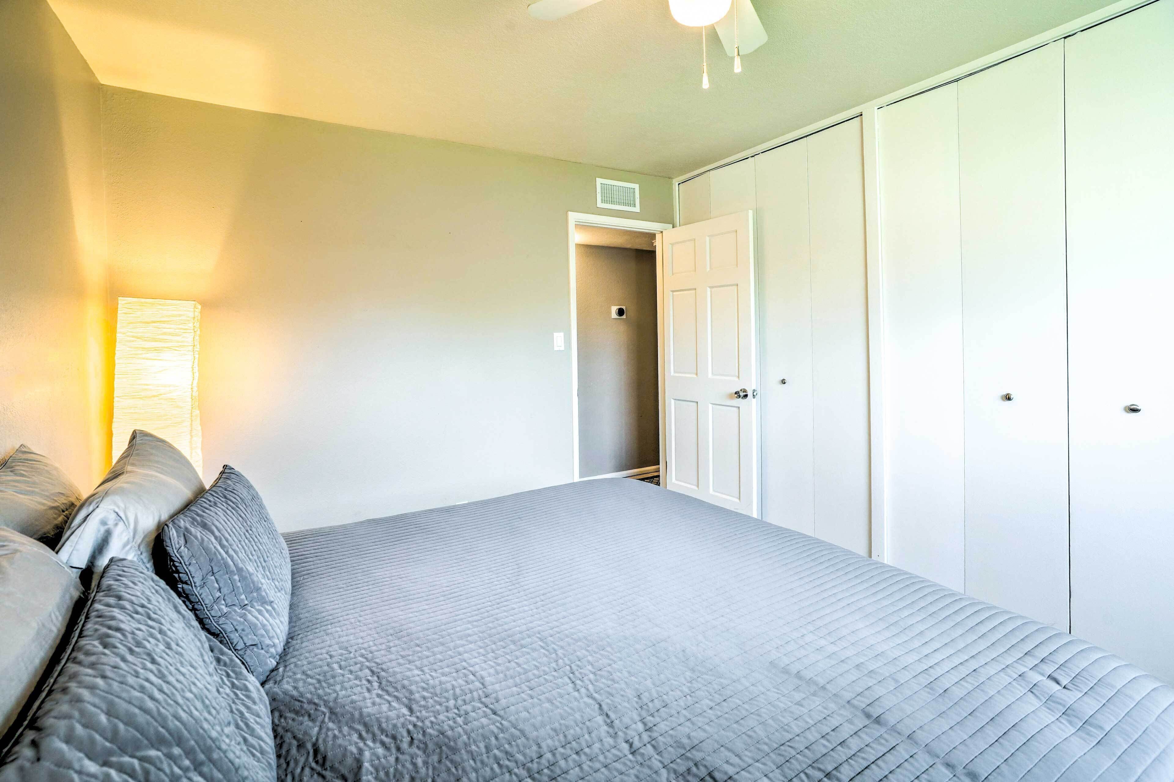 A bedroom with a bed, a nightstand, a ceiling fan, and a wardrobe.