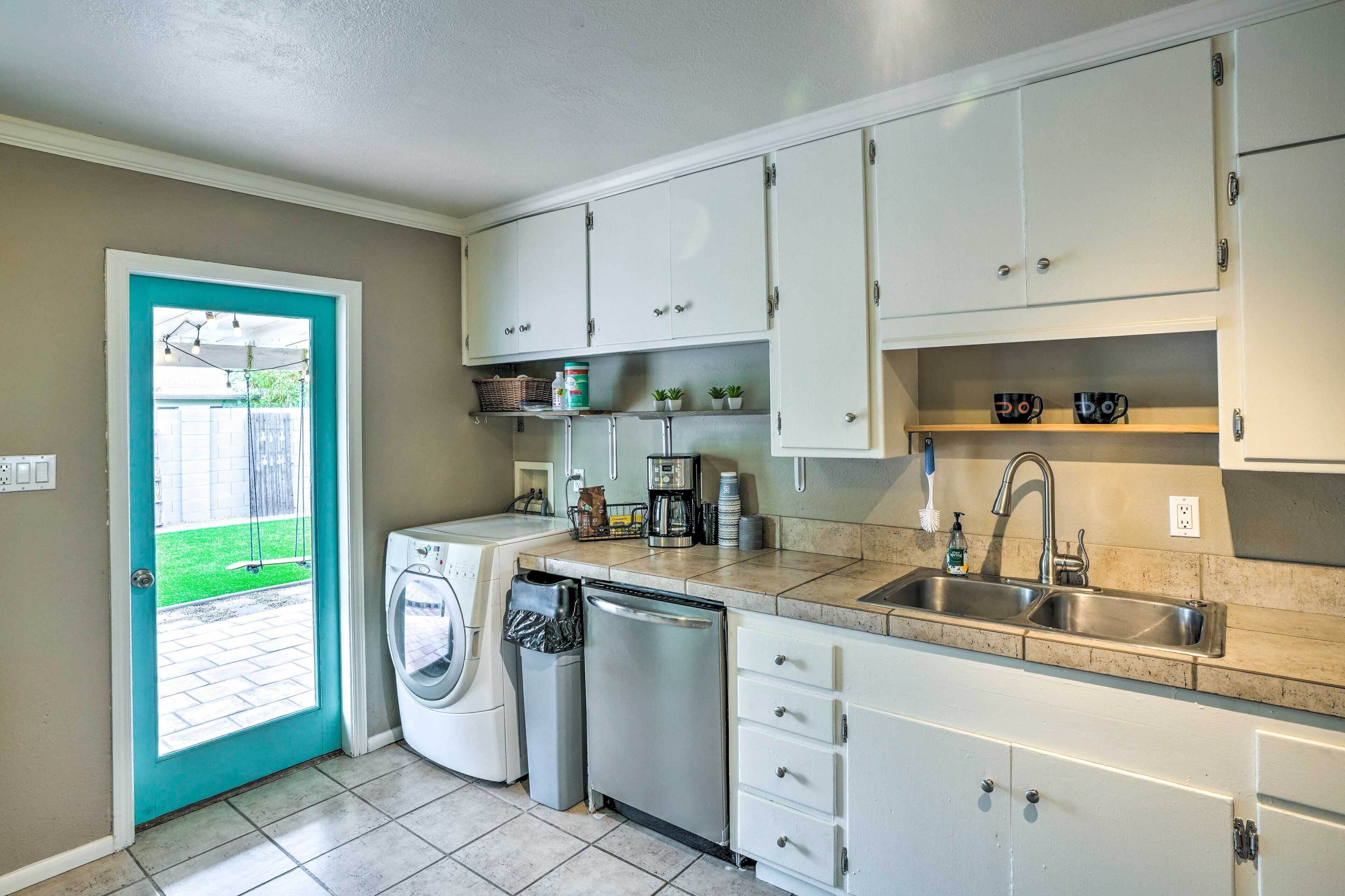 A compact kitchen with white cabinets, a sink, a dishwasher, and a washing machine.