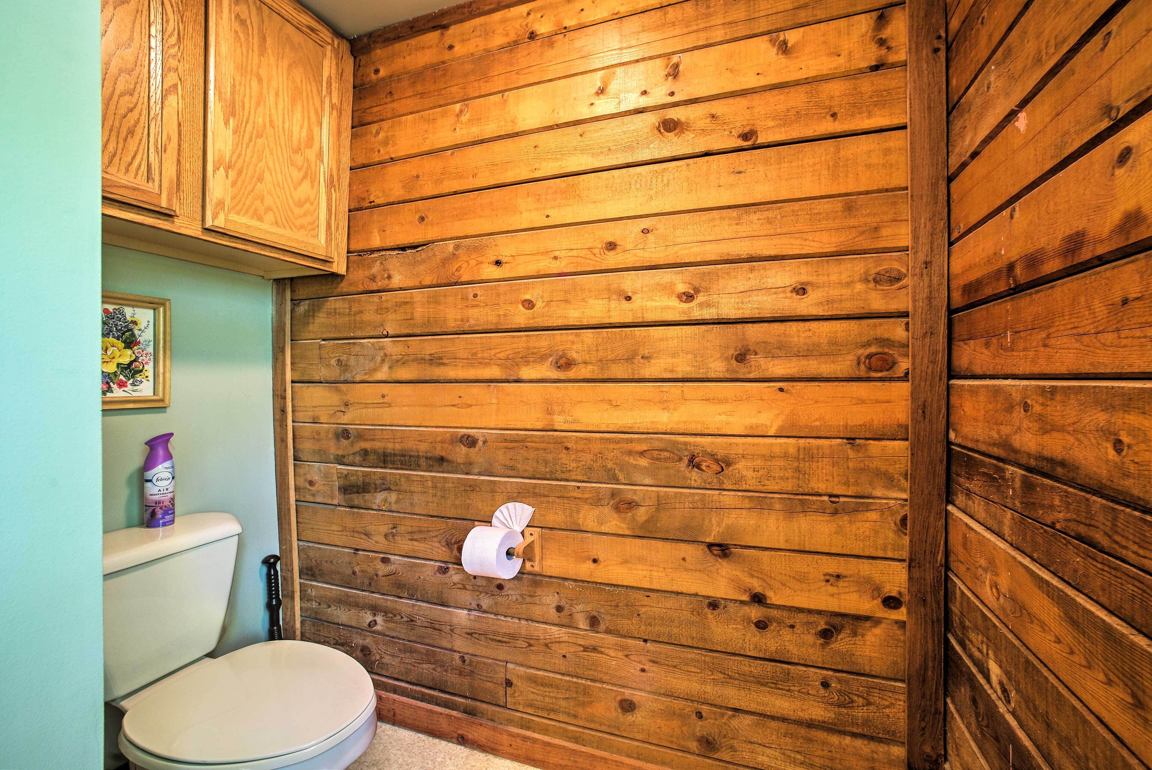 Une salle de bain avec des lambris en bois, des toilettes et un porte-rouleau de papier toilette.