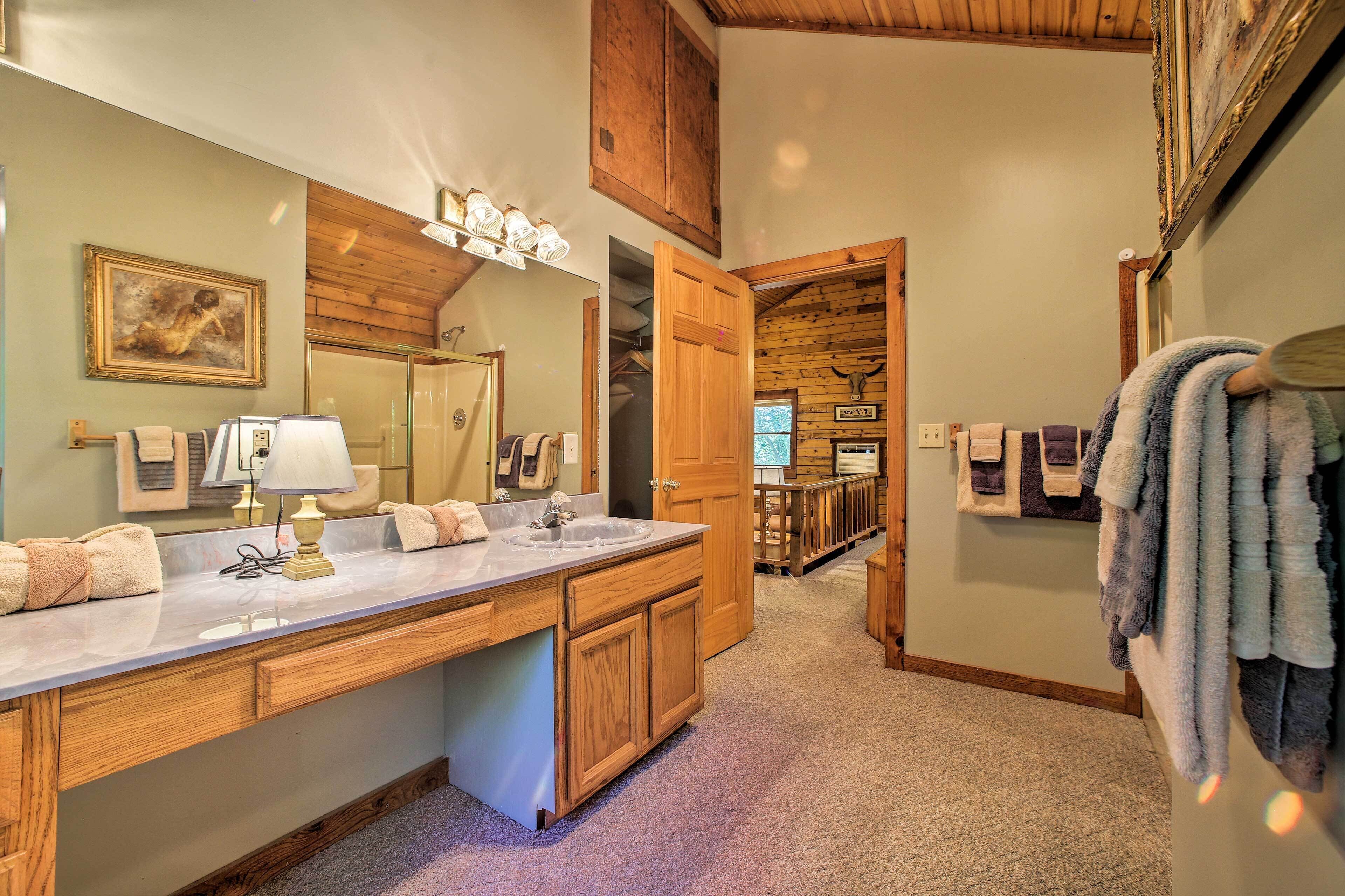 A bathroom with wooden cabinets, a large mirror, and a sink.