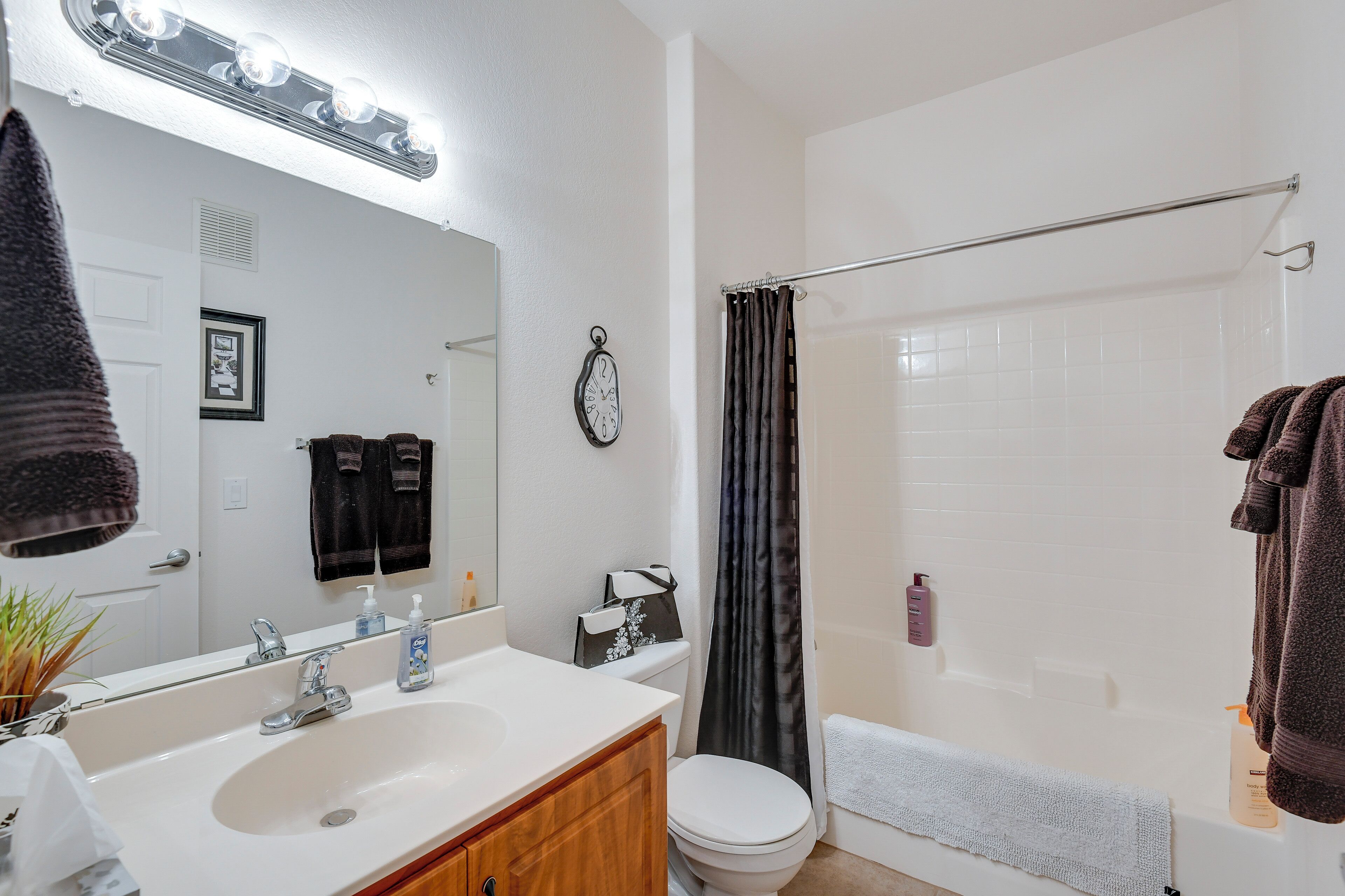 A bathroom with a white sink, mirror, and toilet. There is a shower curtain and a towel rack.