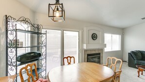 A dining area with a wooden table and chairs, a metal decorative shelf, and a hanging light fixture. - Pet-friendly Escape w/ Grill, 11 Mi to Strip! (North Las Vegas)