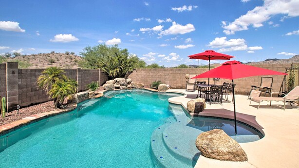 A backyard with a swimming pool, red umbrellas, and outdoor furniture. - Goodyear Home w/ Pool, Quiet Walkable Community (Goodyear)