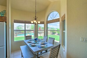 A dining area with a table set for four, large windows, and a view of a backyard. - Goodyear Home w/ Pool, Quiet Walkable Community (Goodyear)