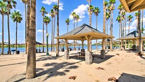 A beach with palm trees, a gazebo, and picnic tables. - Goodyear Home w/ Pool, Quiet Walkable Community (Goodyear)