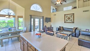 A spacious living area with a large island, seating arrangements, and a balcony with a view. - Goodyear Home w/ Pool, Quiet Walkable Community (Goodyear)