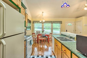 Una cocina con una mesa de comedor, sillas, refrigerador, estufa y una ventana con persianas.