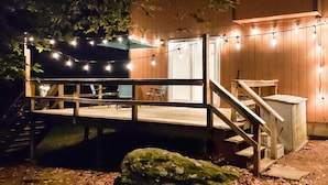 Une terrasse en bois agrémentée de guirlandes lumineuses, d’un escalier et d’une petite table.
