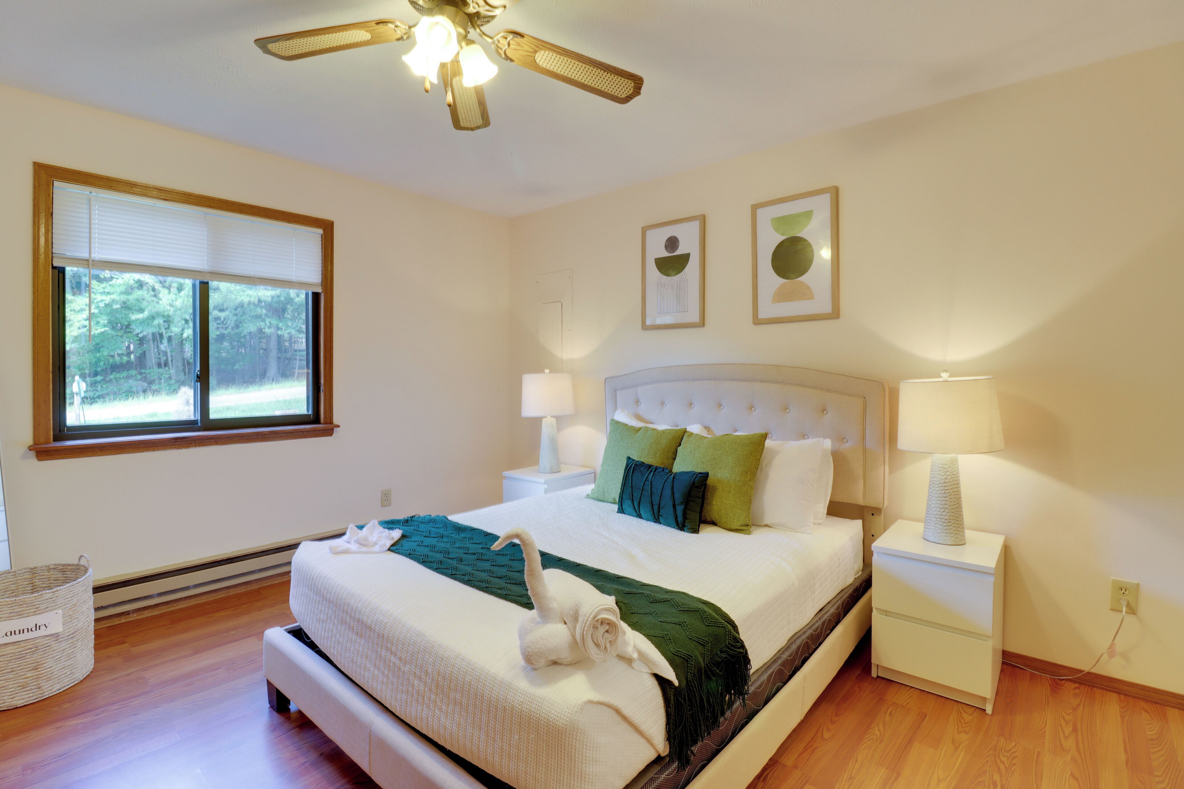 Une chambre à coucher avec un lit, des lampes de chevet, un ventilateur de plafond et une fenêtre avec des stores.
