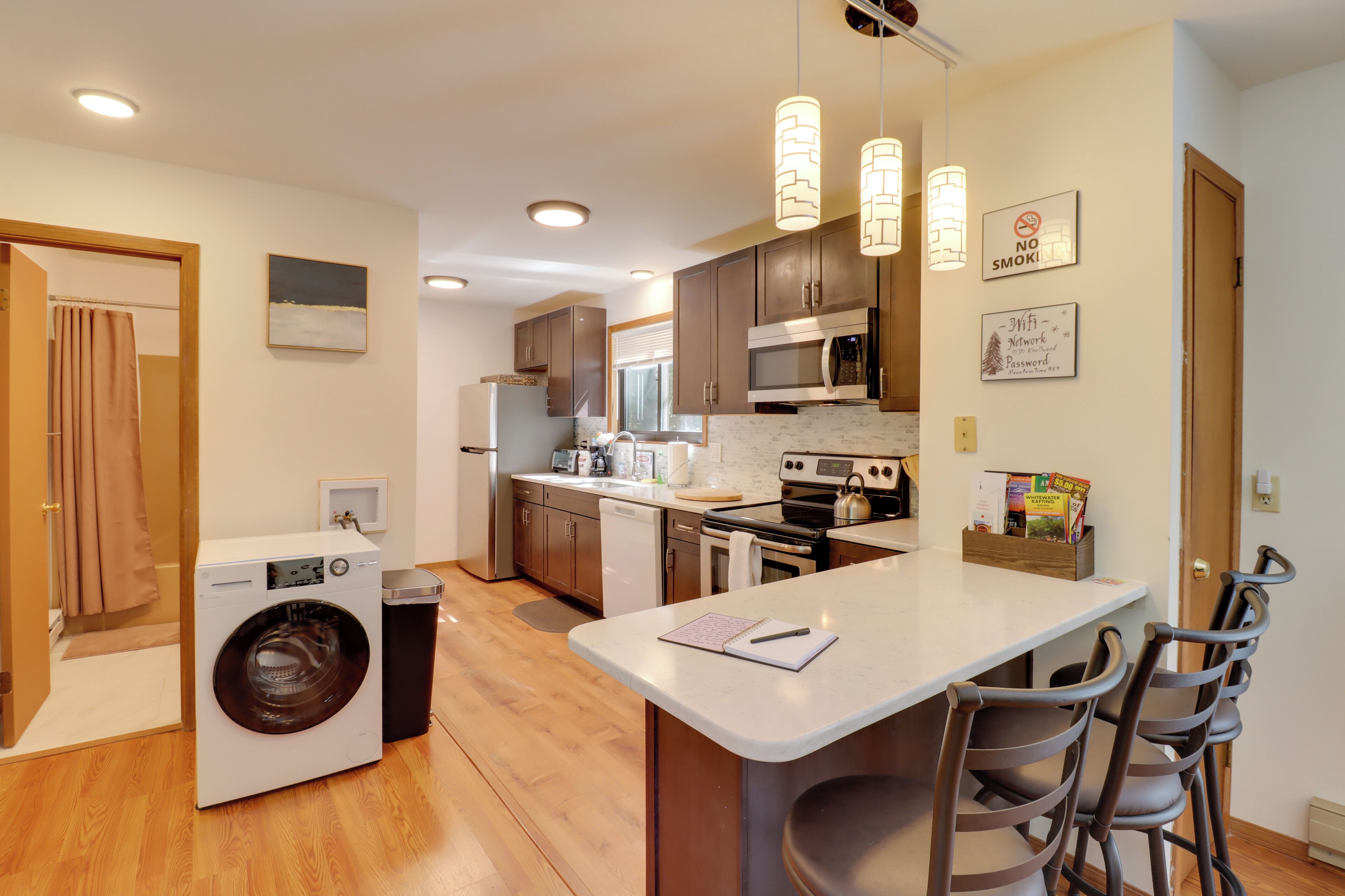 A modern kitchen with a central island, built-in appliances, and a dining area with bar stools.
