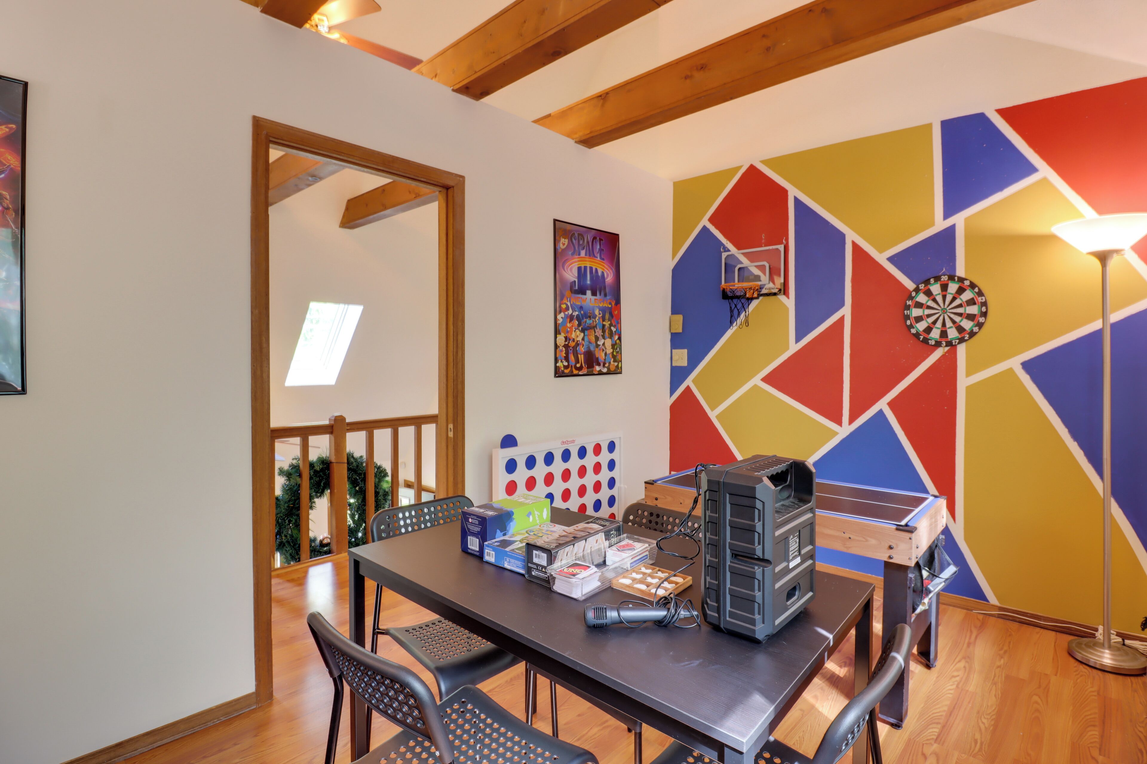 A dining area with a table set for four, a dartboard, and a ping pong table.
