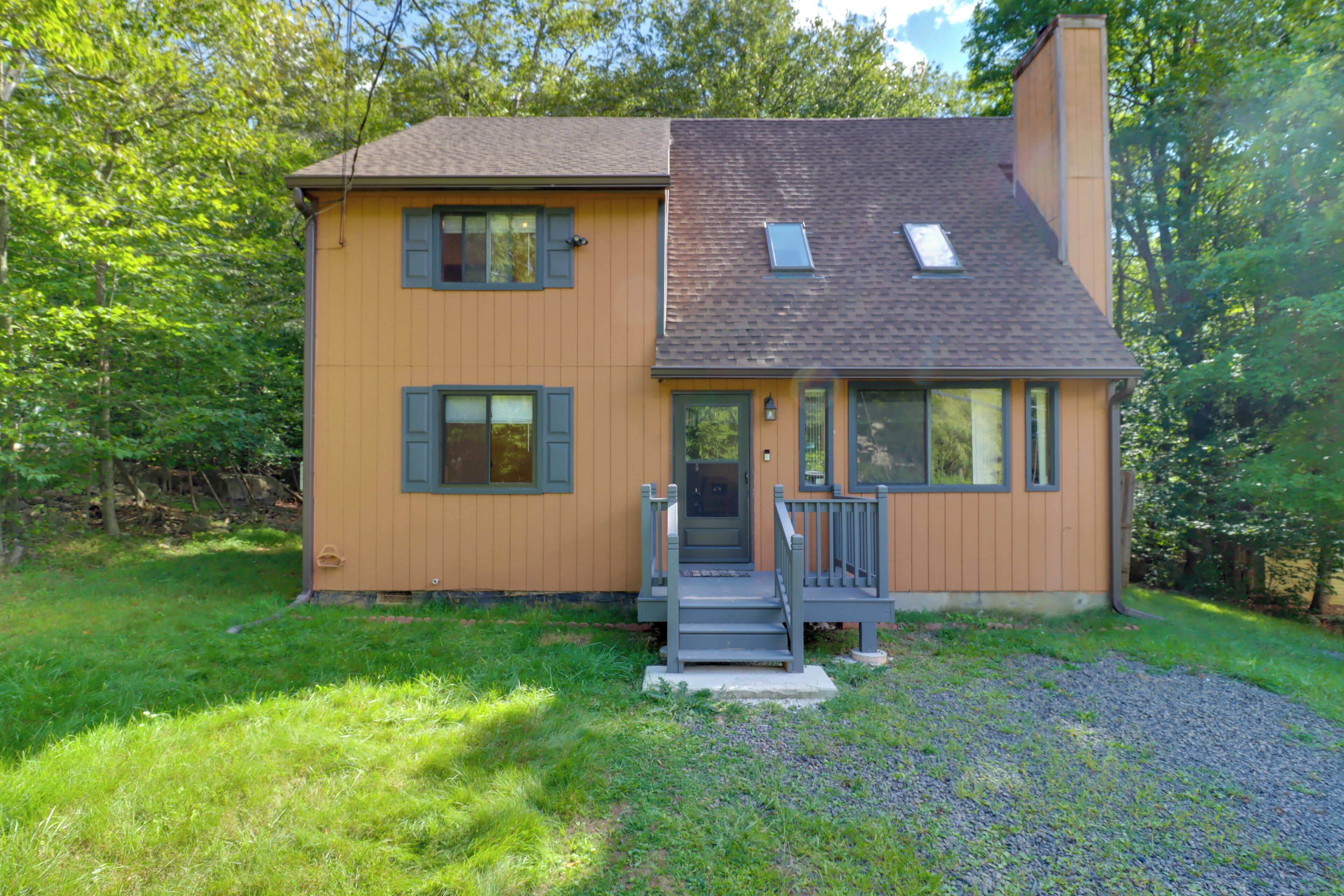 A two-story house with a front porch, a chimney, and a small window on the roof.