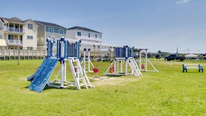 A playground with slides and swings, surrounded by a grassy area and buildings in the background. - Sunsets, Salt Air and Single-story Ease in Fenwick (Selbyville)