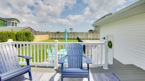 A deck with two blue Adirondack chairs, a white fence, and a view of a backyard. - Sunsets, Salt Air and Single-story Ease in Fenwick (Selbyville)
