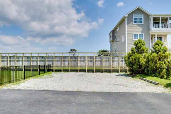 A two-story building with a balcony, a gravel driveway, and a fence.