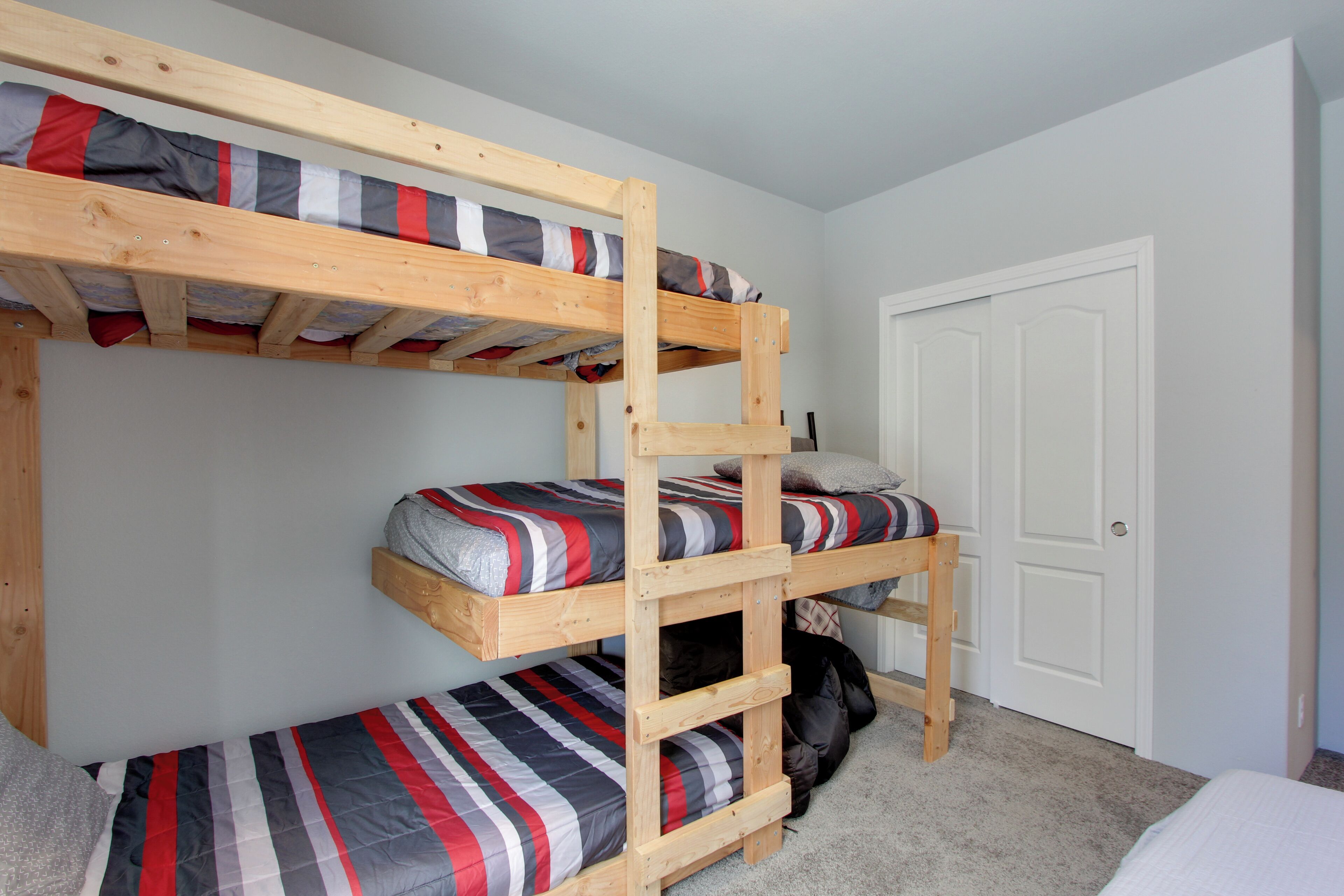 A bunk bed room with a door and a suitcase on the floor.