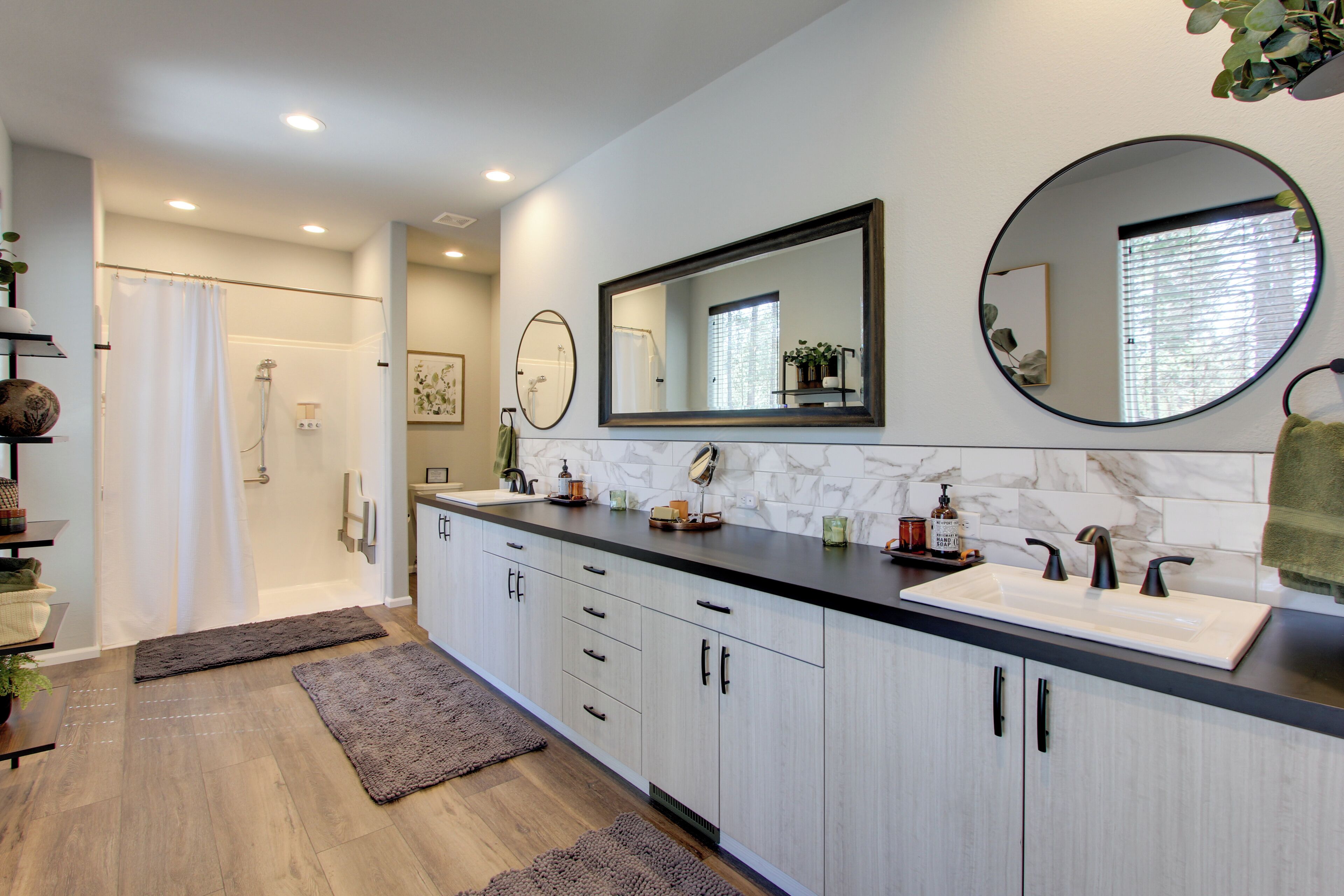 A modern bathroom with a double sink, a large mirror, and a shower area.