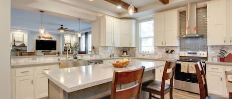 A spacious kitchen with a large island, white cabinetry, and modern appliances.