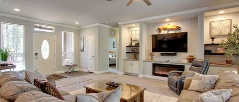 A spacious living room with a large sofa set, a coffee table, and a fireplace.