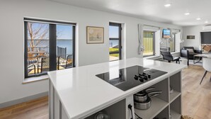A modern kitchen with a large island, a dining area with a view of the outdoors, and a living space with a TV and seating. - Private Sauna, Hot Tub, Beach Lake Poinsett (Lake Norden)