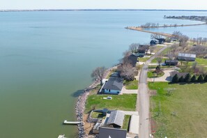 Vue aérienne d’un quartier résidentiel au bord d’un lac, avec des maisons, une jetée et une vue dégagée sur le lac.