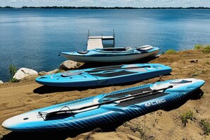 Eine Anlegestelle mit Kajaks und einem Stand-Up-Paddleboard an einem ruhigen See.